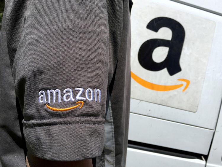 An Amazon.com Inc driver stands next to an Amazon delivery truck in Los Angeles, California, U.S. on May 21, 2016