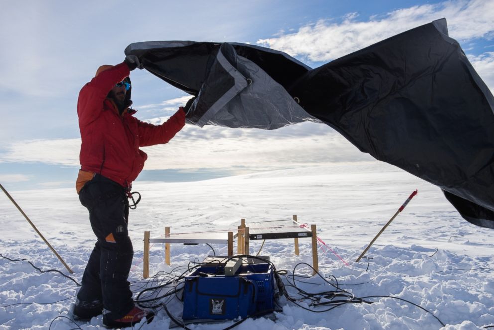 PHOTO: Dr. Paul Bedrosian covers the geophysics equipment before leaving it on a glacier to collect data. 
