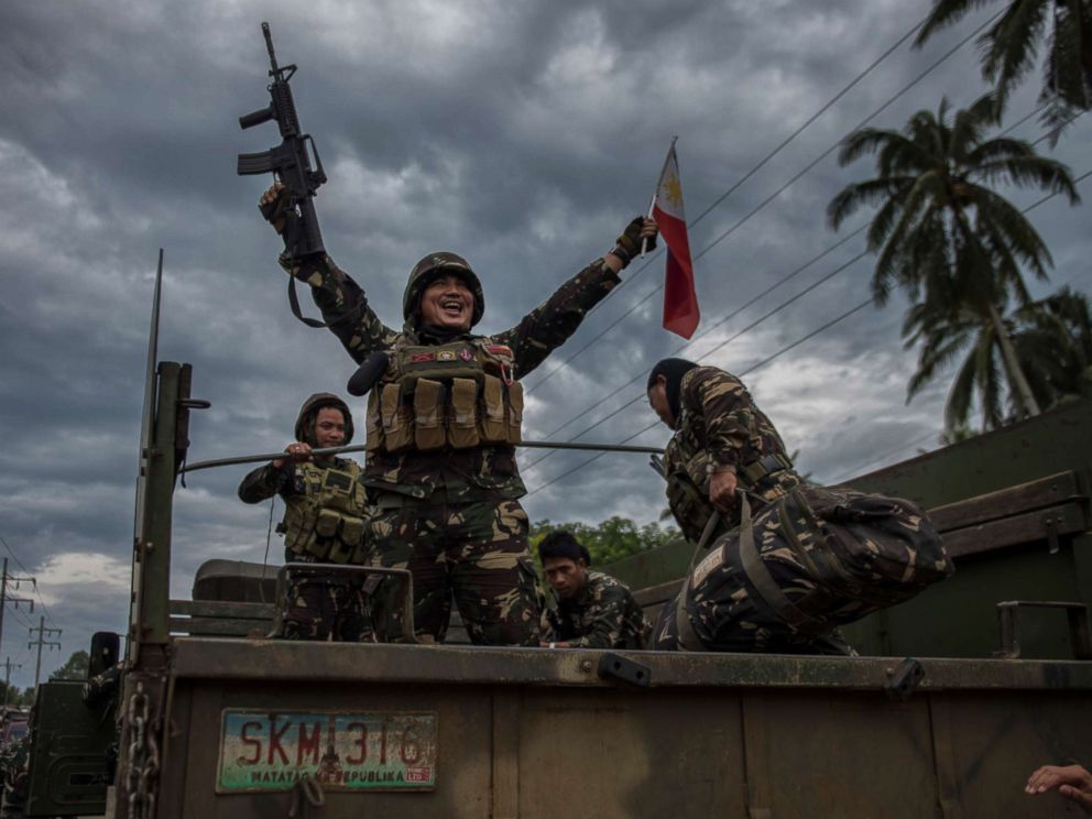 PHOTO: A government soldier waving the Philippine flag as they get ready to leave the battle against IS-inspired militants, Oct. 20, 2017, in Saguiaran town in Lanao del Sur, southern Philippines. 