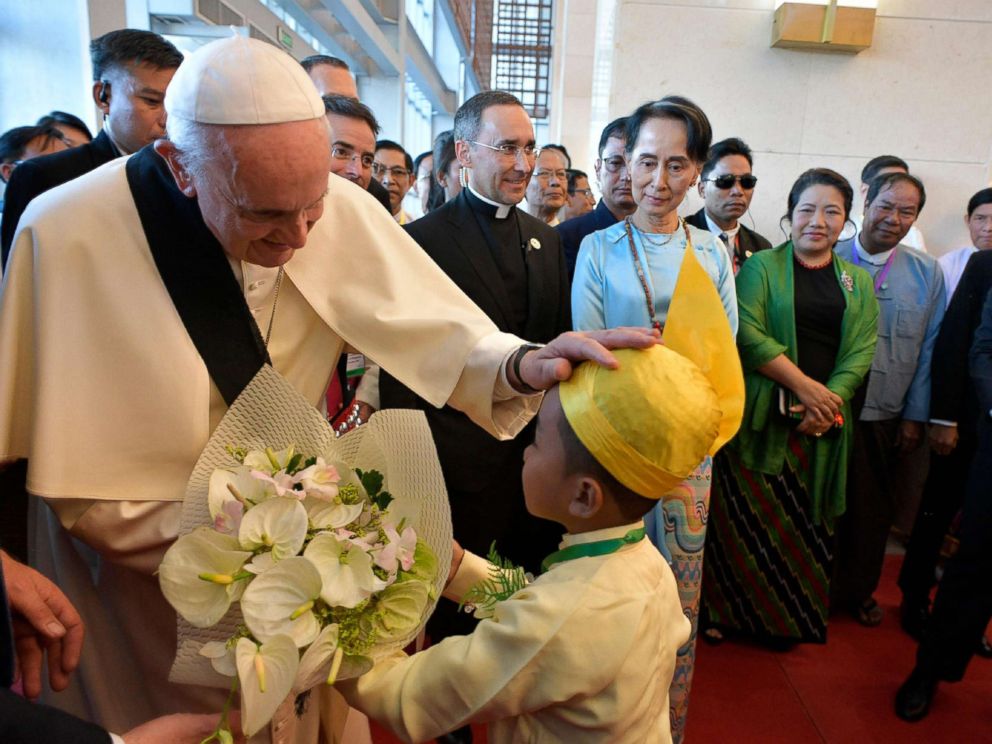 PHOTO: This handout picture taken and released by the Vatican press office (Osservatore Romano) on Nov. 28, 2017, shows Pope Francis greeting a child as Myanmars civilian leader Aung San Suu Kyi watches during an event in Naypyidaw. 