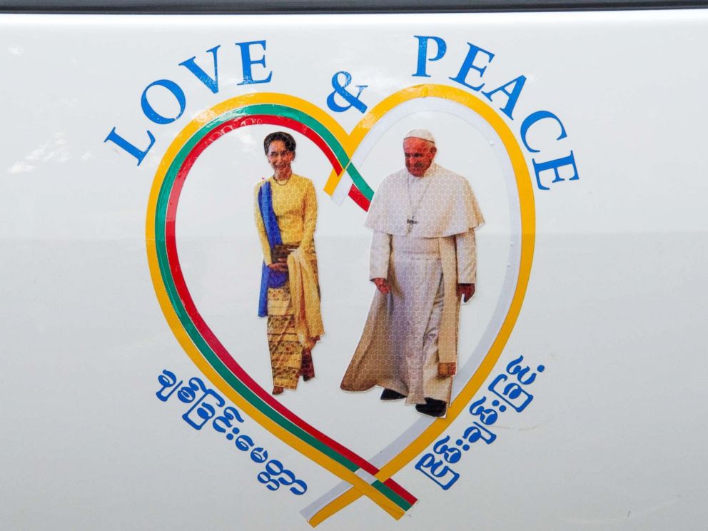 PHOTO: A sticker of Myanmars State Counselor Aung San Suu Kyi (L) and Pope Francis is displayed on a car in the streets of downtown Yangon, after the popes arrival in Myanmar for a four-day official visit on Nov. 27, 2017. 