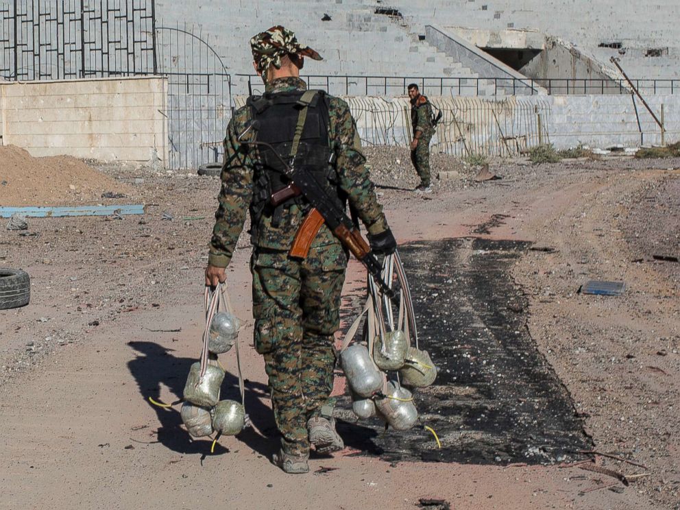 PHOTO: A member of the Syrian Democratic Forces carries bombs they use to destroy IEDs as they clear the stadium where it was the last stand for Islamic State fighters before most fighters handed in and left Raqqa, Syria on Oct. 18, 2017.
