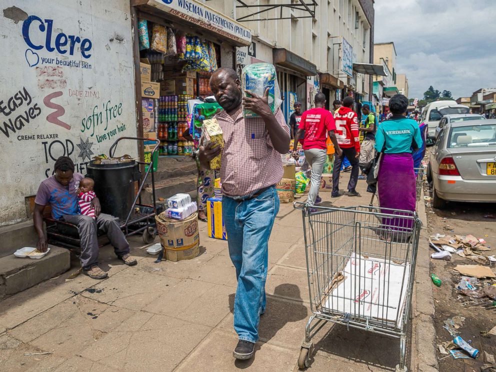 PHOTO: A man carries his wares through a market as business continues in the Zimbabwean capital Harare on Nov. 16, 2017, a day after the military announced plans to arrest criminals close to the president. 