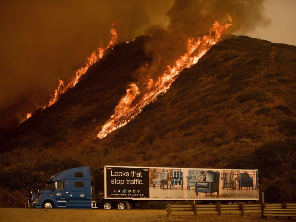 Flames from the Thomas fire burn above a truck on Highway 101 north of Ventura, Calif., on Wednesday, Dec. 6, 2017.