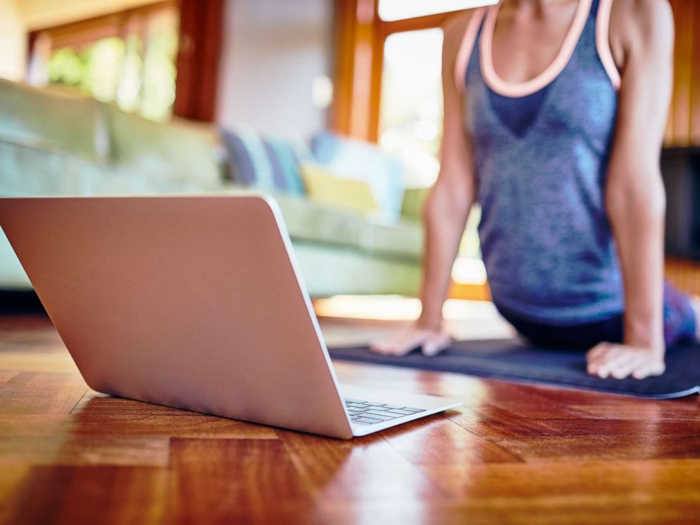 PHOTO: A woman performs yoga at home in front of a laptop computer in an undated stock photo. 