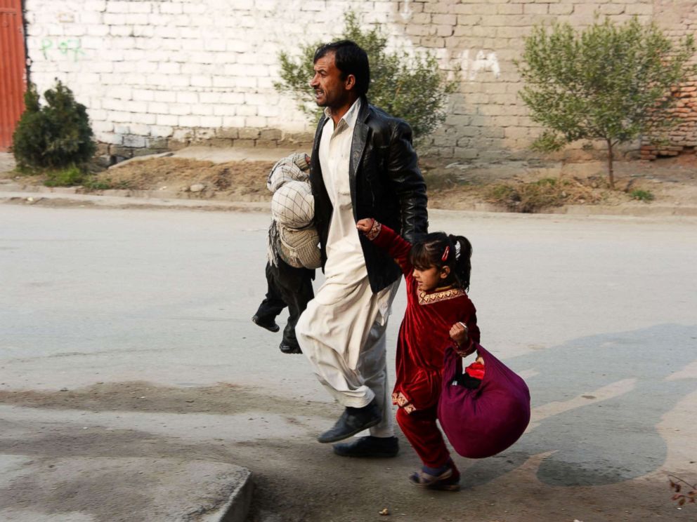 PHOTO: An Afghan man runs with two children near an office of the British charity Save the Children during an attack in Jalalabad, Jan. 24, 2018.