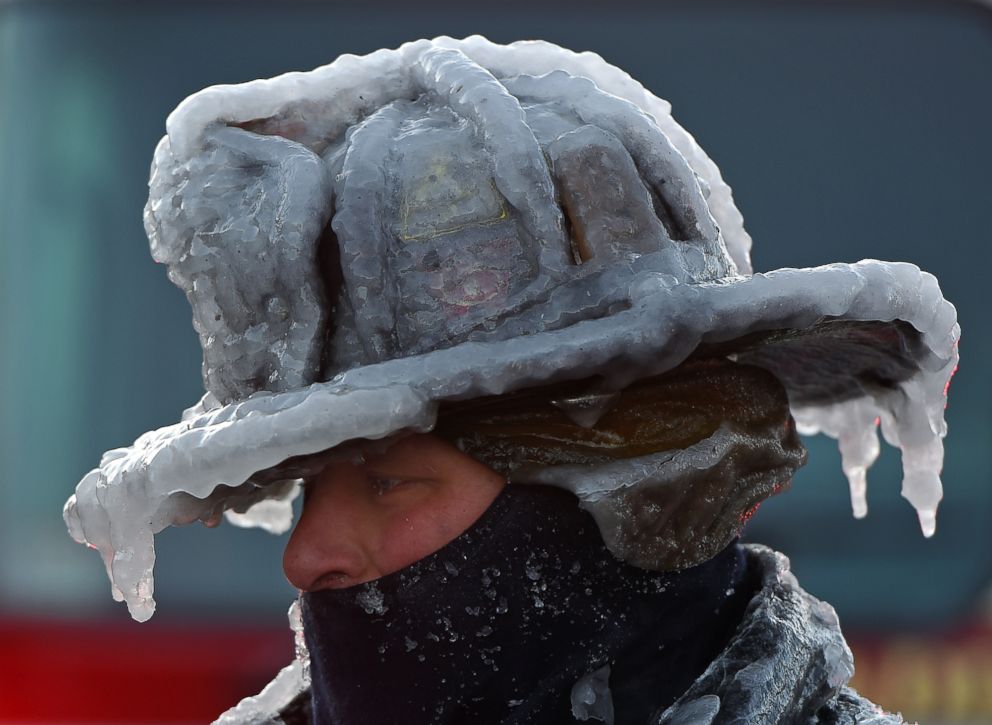 PHOTO: Firefighter Bobby Lehman, with his helmet and bunker gear caked in ice, tries to thaw out after battling a stubborn, wind-driven fire at 238 Wilson Road, Jan. 1, 2018, Nahant, Mass. 