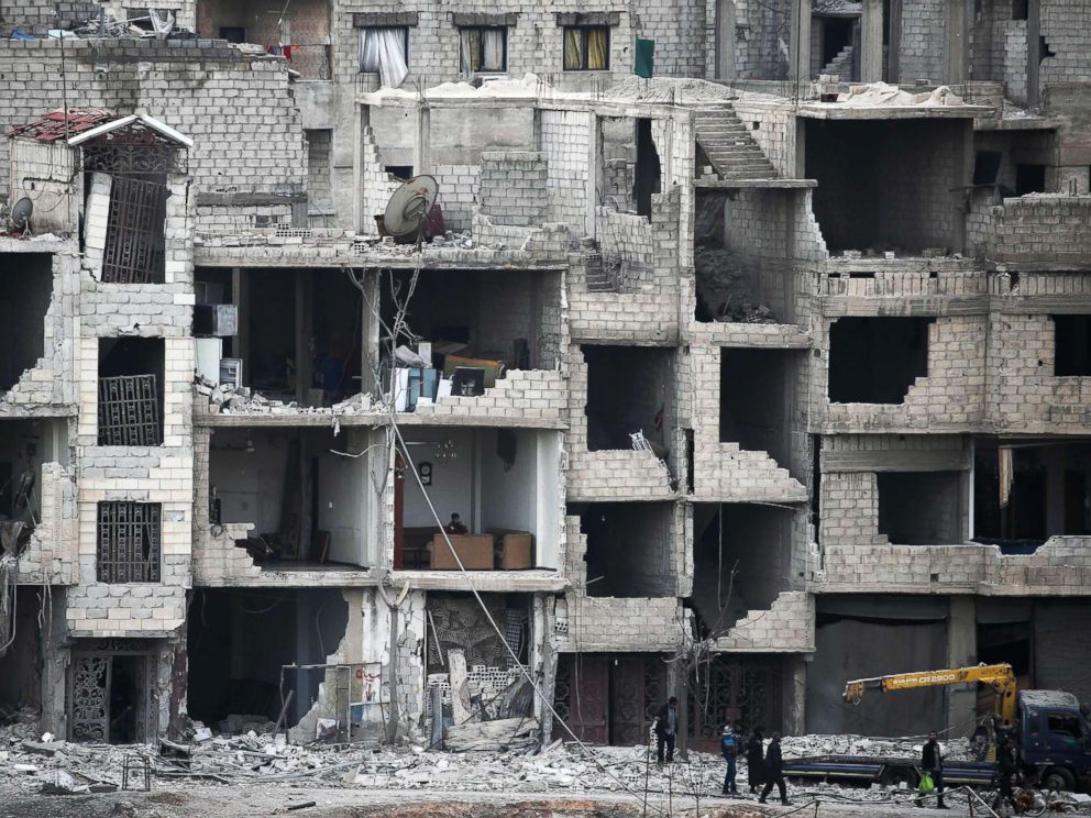 PHOTO: Syrians walk past destroyed buildings in Arbin in the rebel-held enclave of Eastern Ghouta, a suburb of Damascus, Syria, Feb. 25, 2018. <p itemprop=