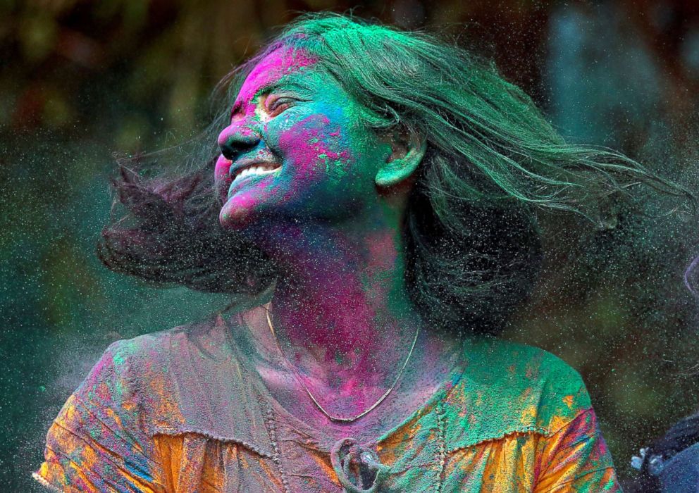 PHOTO: The tradition of throwing colored powder and water is believed to originate from the mythological love story of Radha and Krishna. A woman smeared with colored powder shakes her head during Holi celebrations in Mumbai, India on March 2, 2018. 