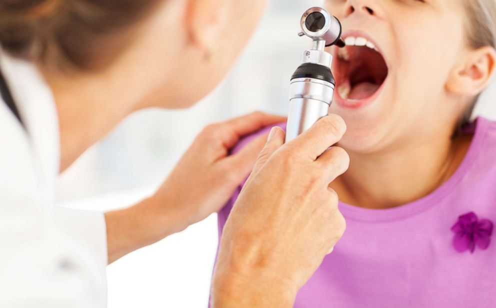PHOTO: A doctor examines a childs throat with otoscope in an undated stock photo.